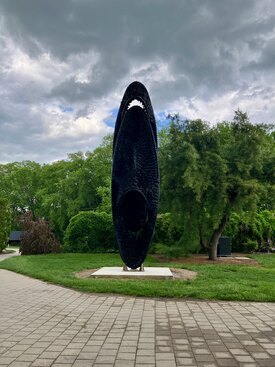 Large cylindrical oval sculpture made of black shredded tire pieces