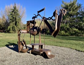 Abstract sculpture made of brown steel, gathered together in the likeness of a women with wild hair.
