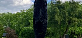 Large cylindrical oval sculpture made of black shredded tire pieces