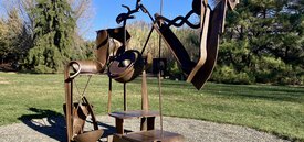 Abstract sculpture made of brown steel, gathered together in the likeness of a women with wild hair.